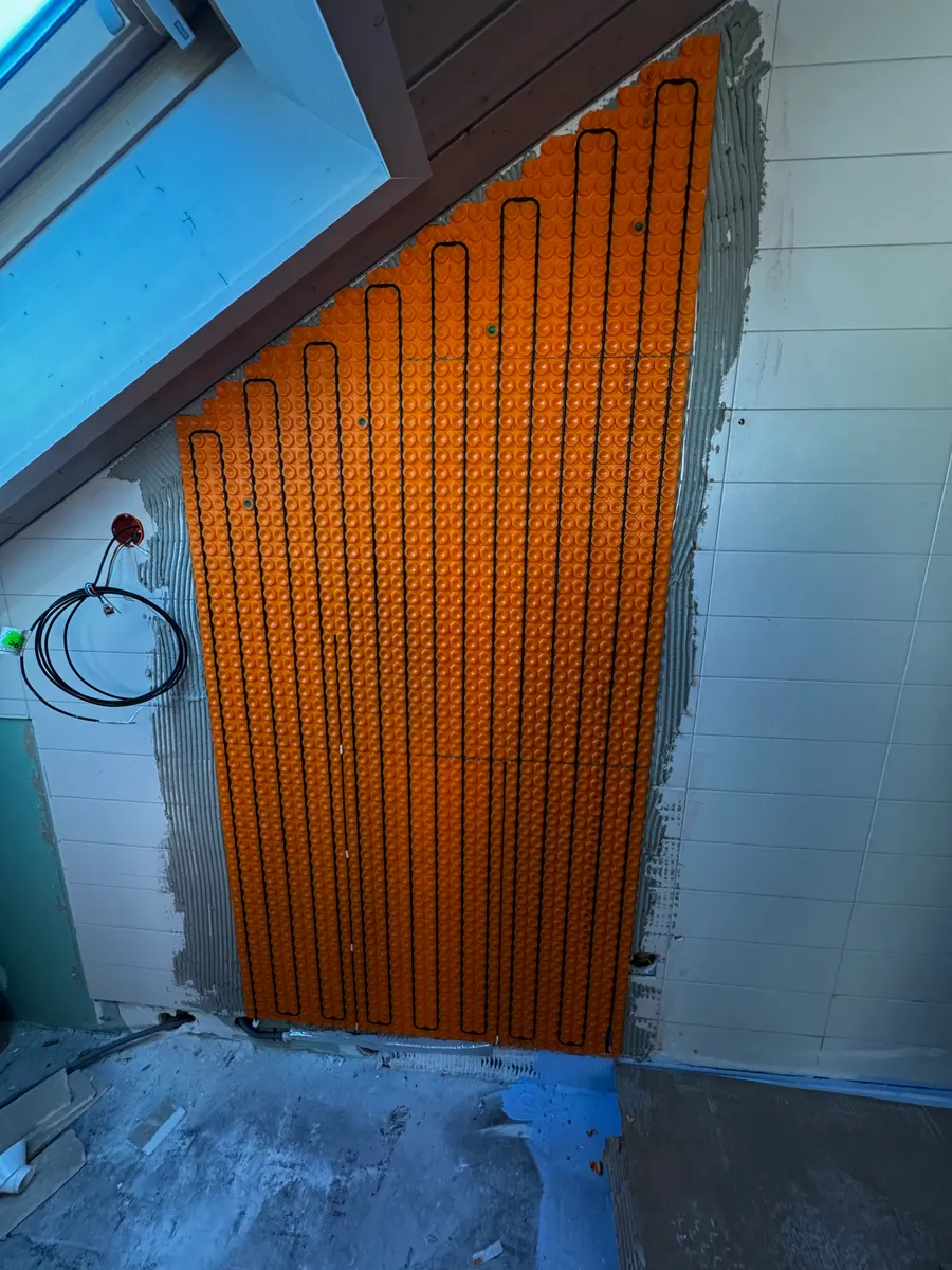 Câble chauffant posé sur un mur de salle de bain sous pente